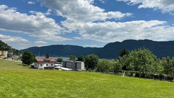 Un champ verdoyant avec un bâtiment et un lac en arrière-plan.