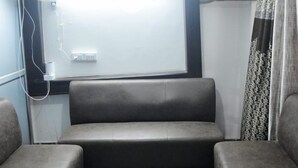 A compact room with a sofa, patterned floor, and a window with curtains. - Lucknow Luxury Hotel And Restaurant (Lucknow)