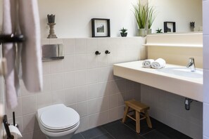 A bathroom with a toilet, sink, and a small wooden stool. - Apartment in Gerlitzen with Panoramic Views (Treffen am Ossiachersee)
