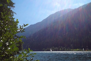 A lake with sailboats, surrounded by forested hills.