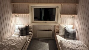 Ein kleiner, gemütlicher Raum mit zwei Einzelbetten, einem Fenster und einer Heizung.
