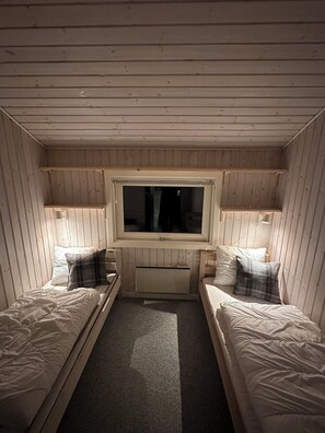 A small, cozy room with two single beds, a window, and a radiator.