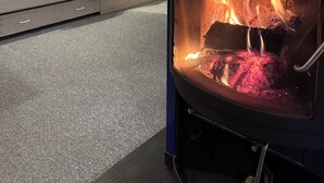 Ein gemütliches Zimmer mit einem Bett, einer Couch und einem Kaminofen.