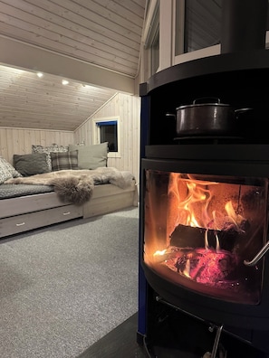 A cozy room with a bed, a sofa, and a wood-burning stove.