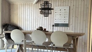 Ein Zimmer mit Holzboden und -wänden, einem Esstisch mit Stühlen, einer Hängelampe und einem Poster an der Wand.