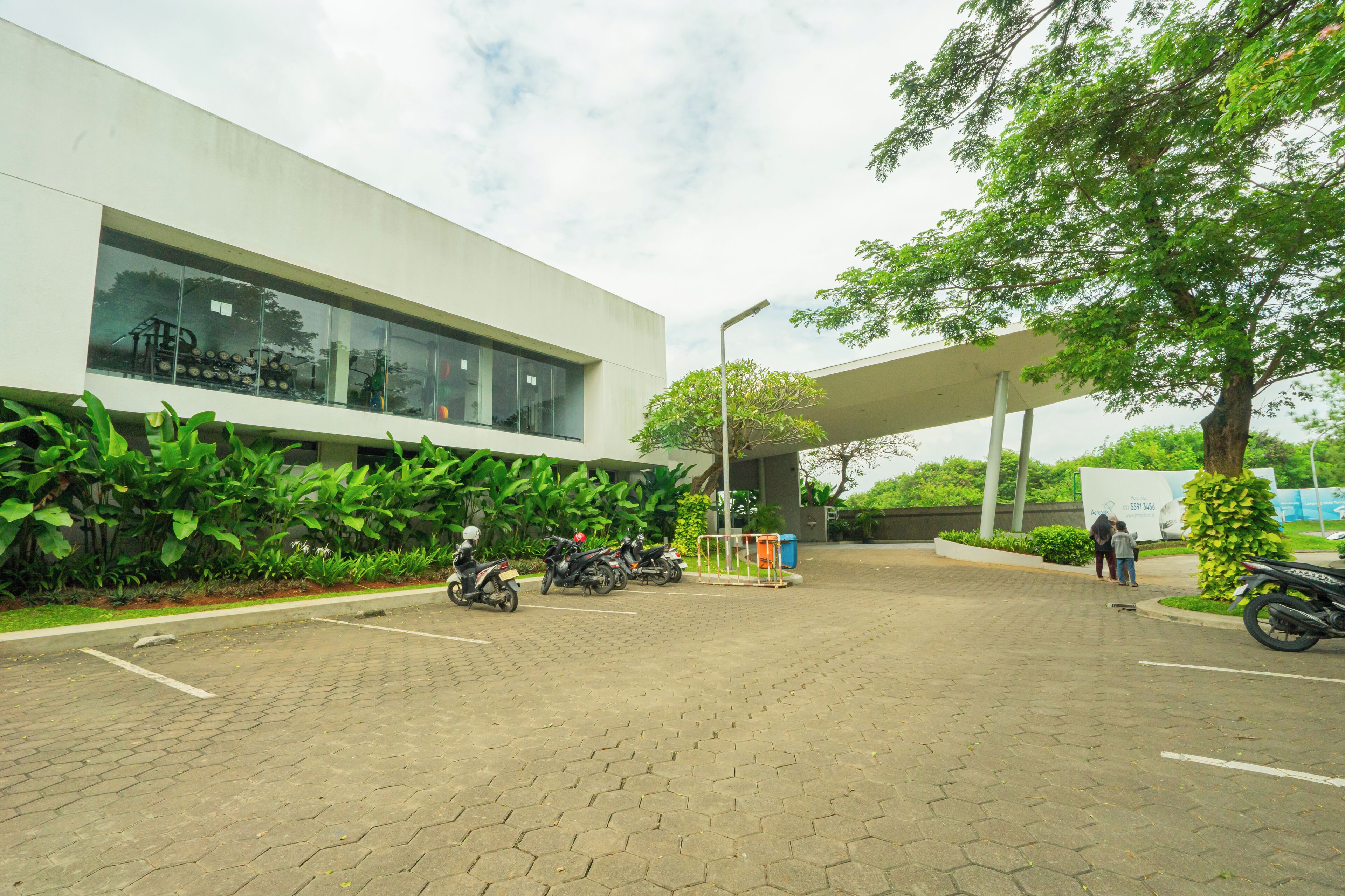 A modern building with large windows, a paved entrance, and several parked motorcycles.