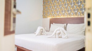 Una cama bien tendida con sábanas blancas y dos toallas suaves dispuestas de forma original.