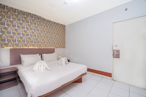 A hotel room with a bed, bedside tables, a wardrobe, and a patterned wall.