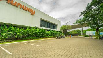 A Runway building with a paved entrance, a motorcycle parked in front, and a person walking.