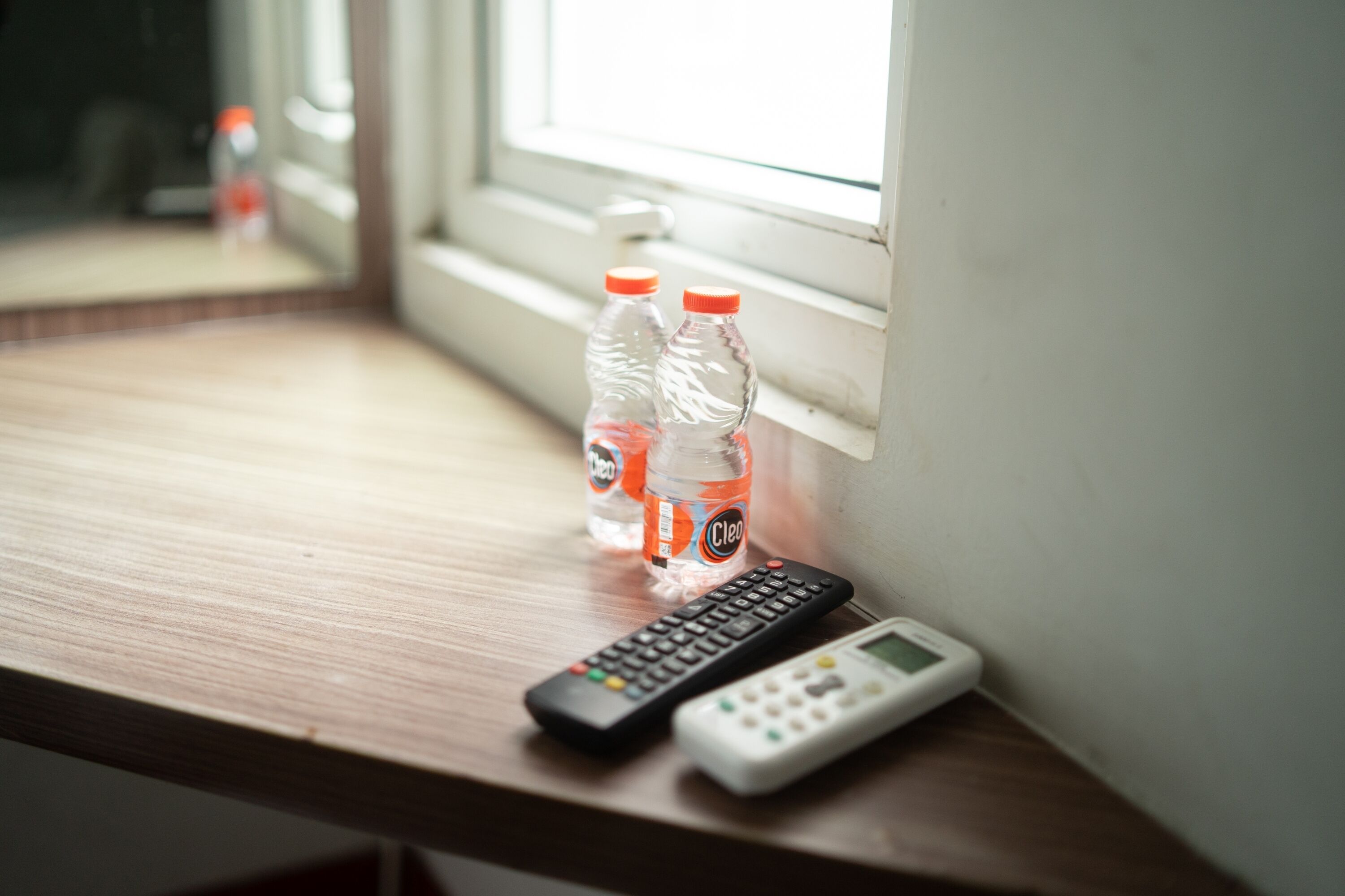 A wooden desk with two bottles of water and a remote control.