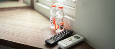 A wooden desk with two bottles of water and a remote control.