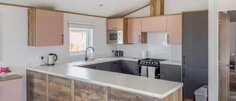 A modern kitchen with a central island, built-in appliances, and a view of the outdoors.