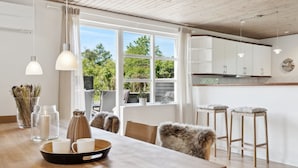 Cocina moderna con armarios blancos, encimera de madera y un amplio ventanal con vistas a la vegetación.