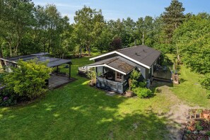 A house with a covered porch, a small deck, and a garden with various plants.