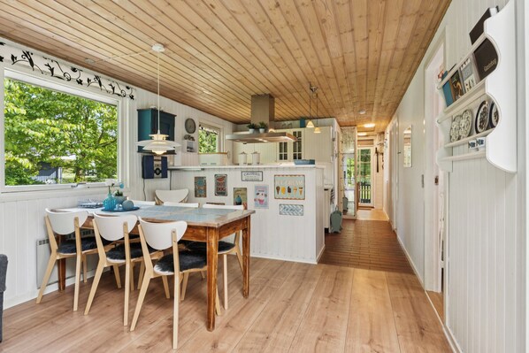 A kitchen with wooden flooring, white cabinetry, and a dining area with a wooden table and chairs.