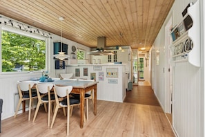 A kitchen with wooden flooring, white cabinetry, and a dining area with a wooden table and chairs.