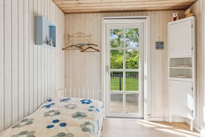 A bedroom with a bed, a wardrobe, a hanging rack, and a door leading to a balcony.