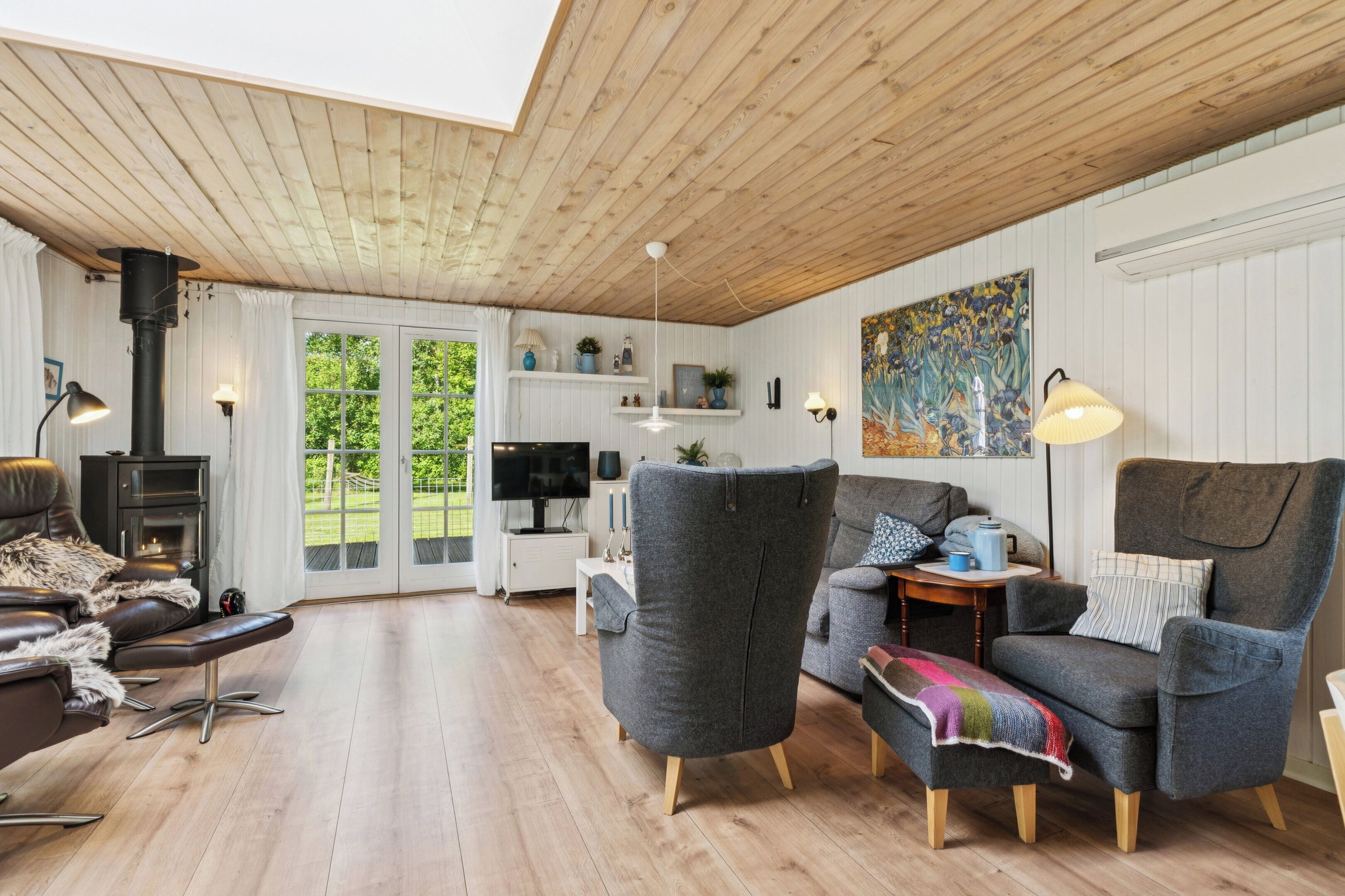 A cozy living room with a fireplace, comfortable seating, and a large window overlooking greenery.