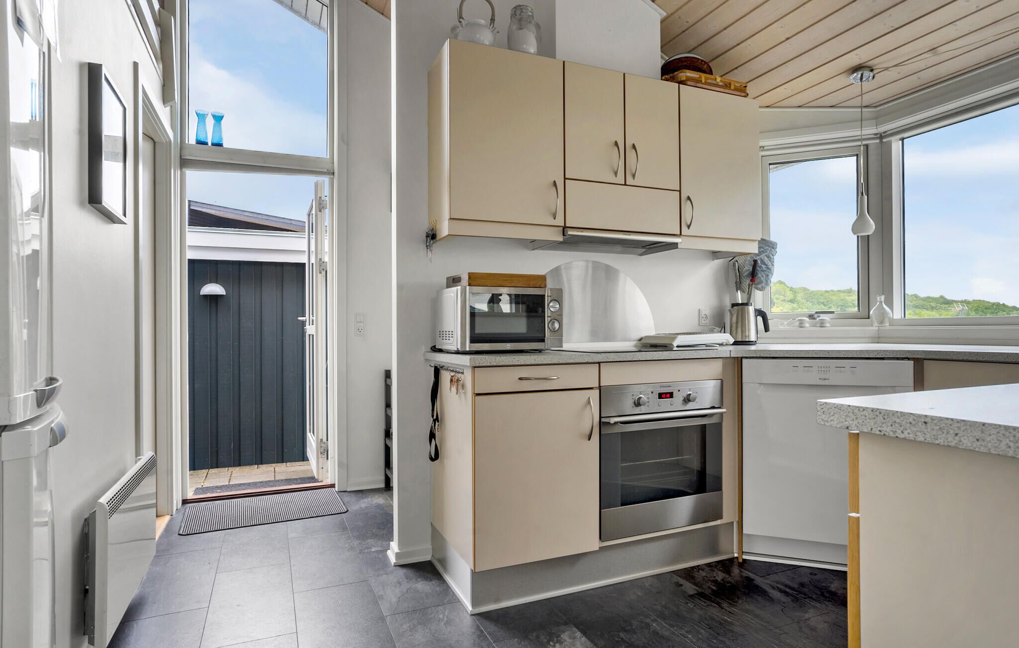 Eine moderne Küche mit Mikrowelle, Backofen und Spüle. Ein Fenster bietet Blick ins Freie.