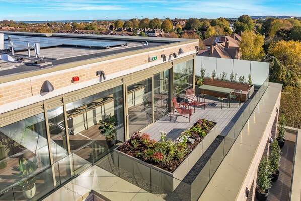A rooftop terrace with glass railings, outdoor seating, and potted plants. - Niche Living Ballsbridge (Dublin)