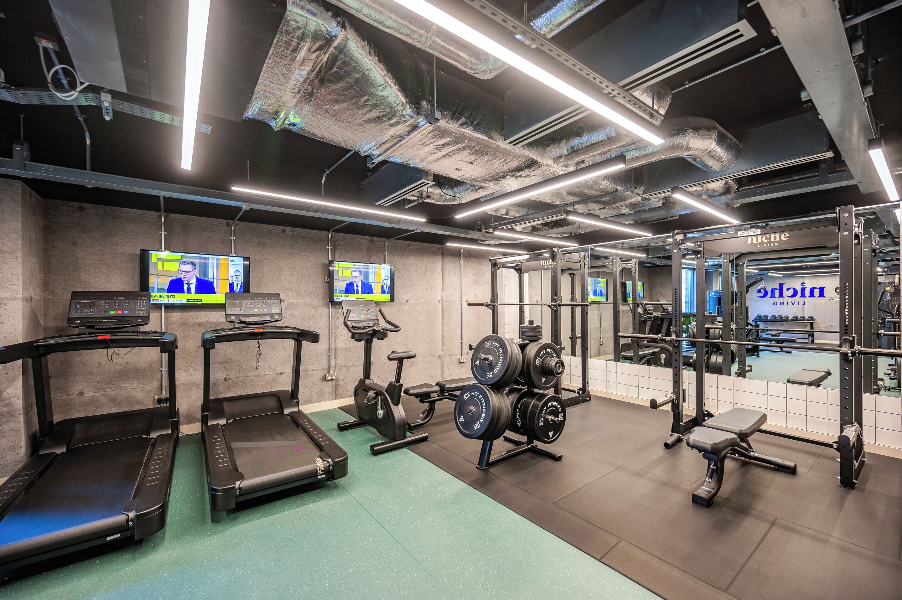 A gym with treadmills, an elliptical, a weight bench, and a mirror.