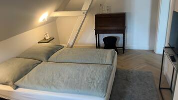 Ein Schlafzimmer mit Bett, Nachttisch, Lampe und einem kleinen Holzkasten.