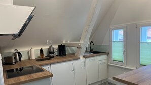Une cuisine moderne avec des meubles blancs, un plan de travail en bois, une machine à café et une bouilloire.