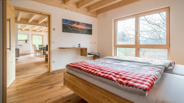 A bedroom with a wooden bed, a painting on the wall, and a large window. - Apartment 'Dollenberg' with Mountain View, Balcony and Wi-Fi (Bad Peterstal-Griesbach)