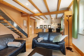 A living room with a sofa, a coffee table, a staircase, and a kitchen area.
