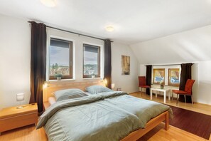 Une chambre à coucher avec un lit, des tables de chevet, une fenêtre avec des rideaux, une petite table et une chaise.
