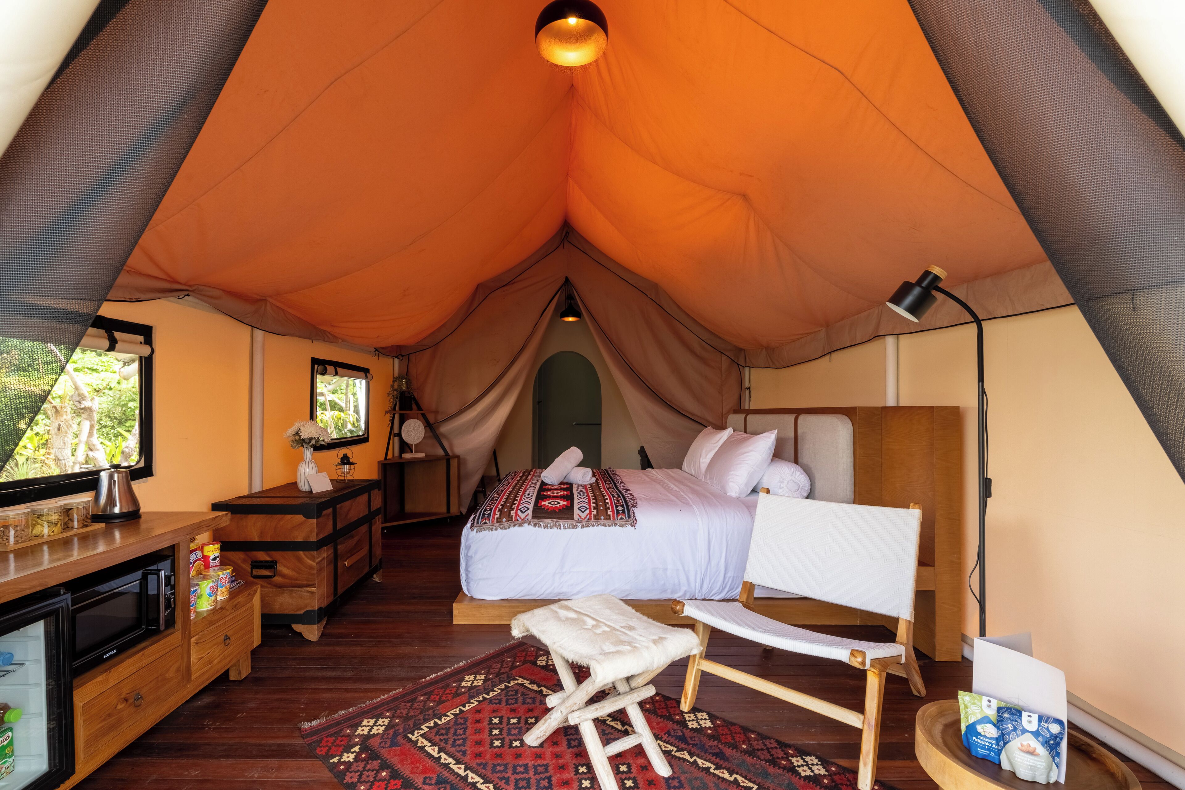 A tent with a bed, a desk, a chair, and a small stool.