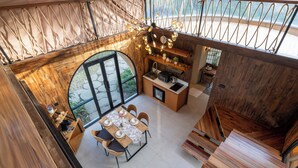 A modern kitchen with wooden accents, a dining area with a large window, and a staircase with wooden steps. - Sanctua Resort Bedugul (Baturiti)