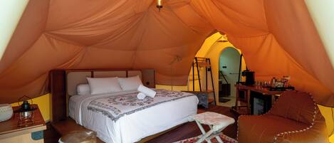 A tent with a bed, a small table, a chair, and a rug.