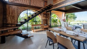 A dining area with a wooden table set for four, a bench, and a staircase leading to an upper level. - Sanctua Resort Bedugul (Baturiti)