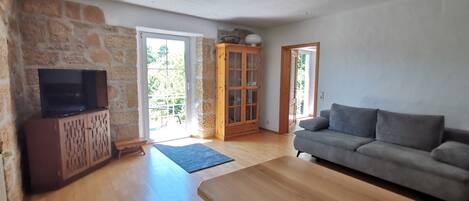 Un salon avec un meuble TV en bois, un canapé gris et un buffet en bois.