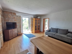 Un salon avec un meuble TV en bois, un canapé gris et un buffet en bois.