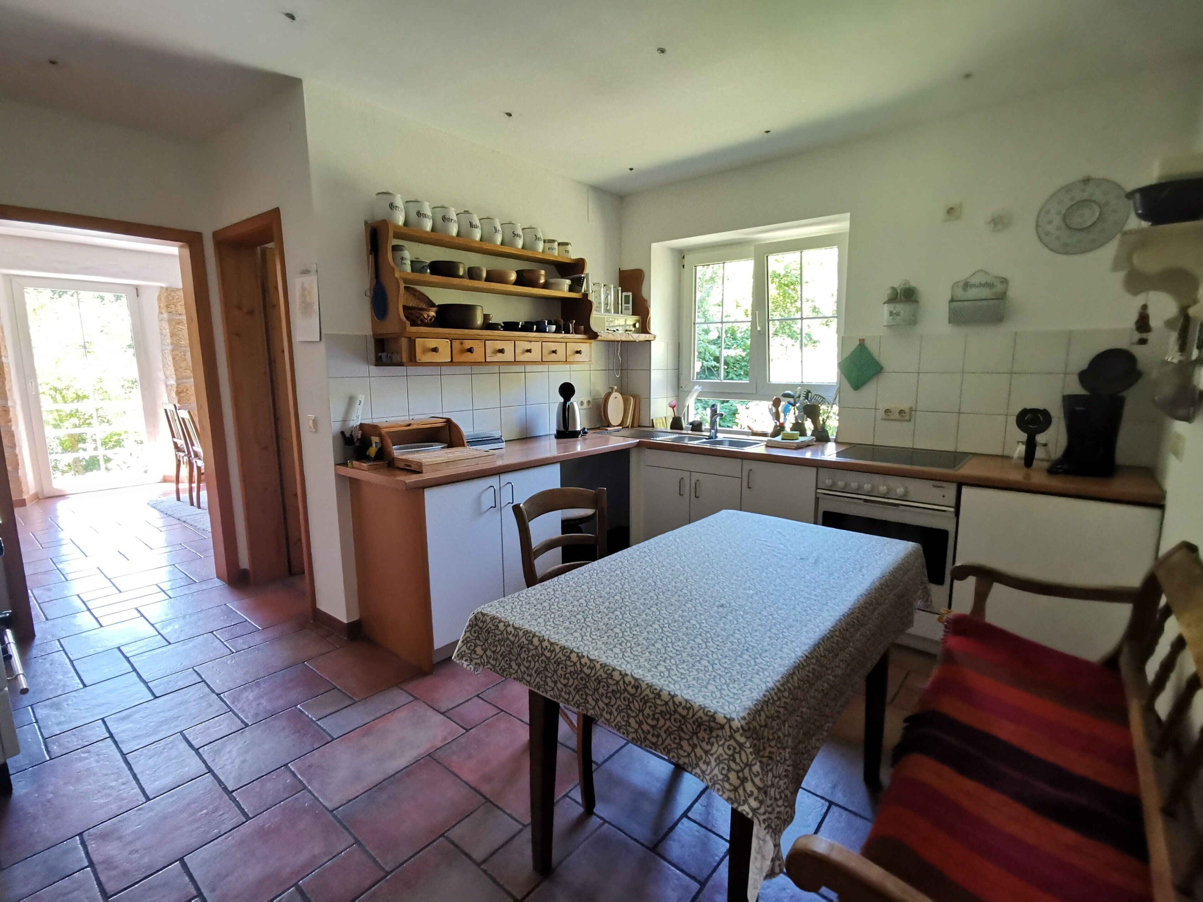 Une cuisine comprenant une table à manger, des chaises, une fenêtre et une porte donnant sur un espace extérieur.
