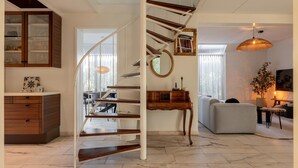 Ein modernes Interieur mit Wendeltreppe, Essbereich und Wohnbereich inklusive Sofa und Lampe.