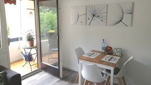A room with a sliding glass door leading to a balcony, a wooden table with chairs, and three wall-mounted abstract art pieces. - Apartment 'Lived-in' with Mountain View, Balcony and Wi-Fi (Bad Urach)