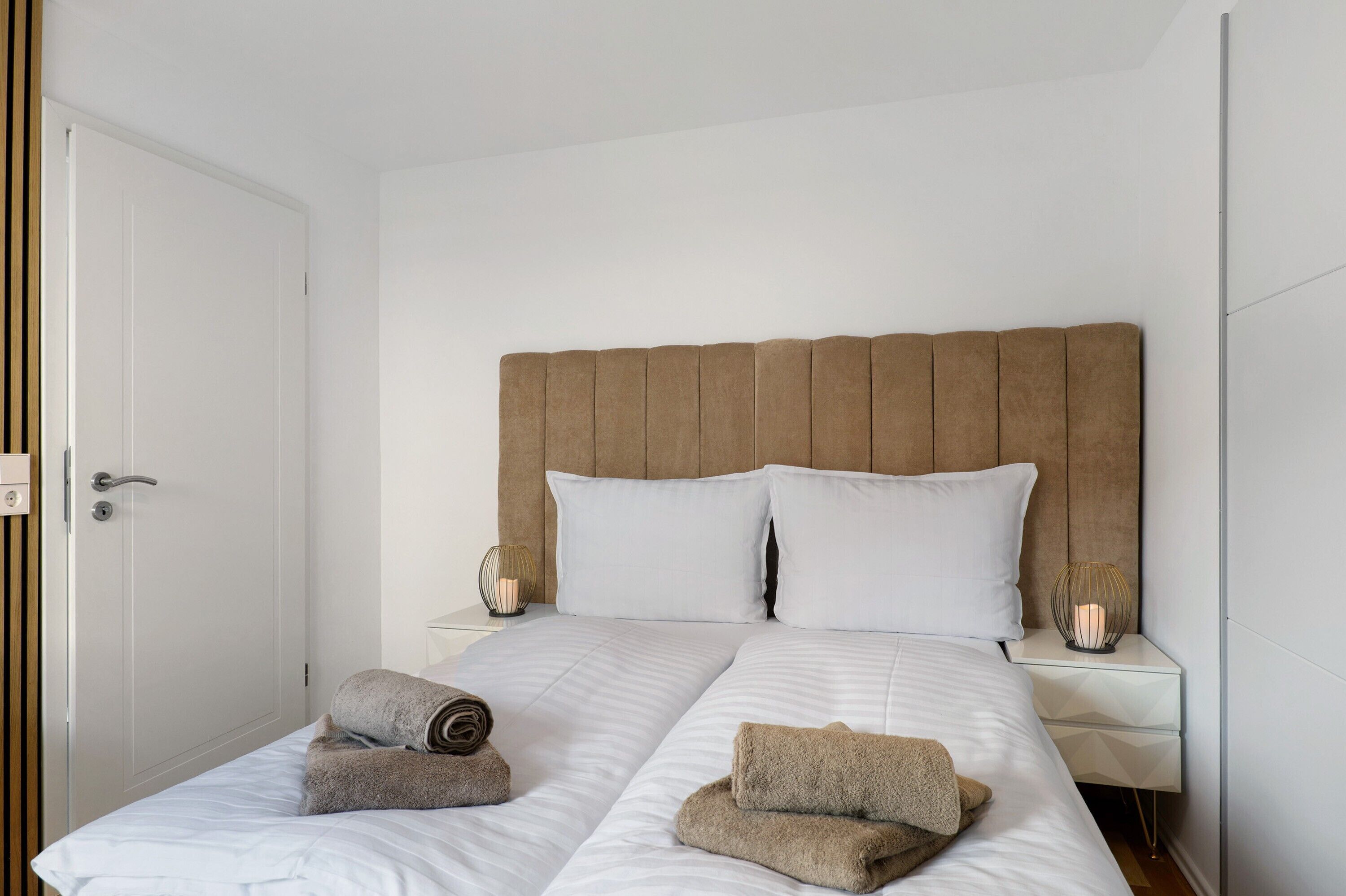 Une chambre d’hôtel avec un lit, deux oreillers, une table de chevet avec une lampe et une porte.