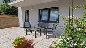 A modern outdoor patio with a table and chairs, a potted plant, and a climbing plant. - Apartment 'Ferienwohnung' with Private Terrace, Private Garden and Wi-Fi (Sinsheim)