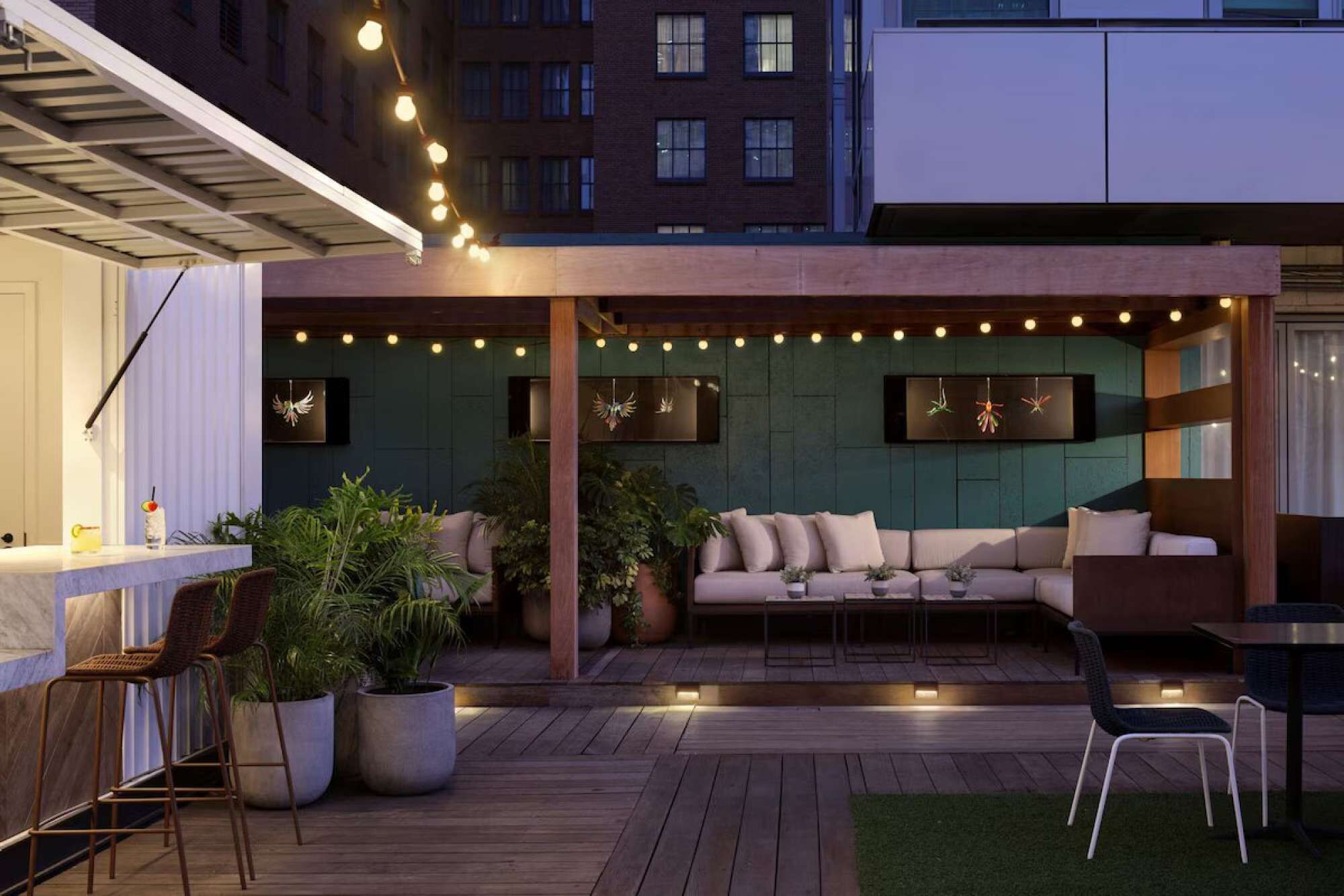 Eine Terrasse im Freien mit Holzboden, gepolsterten Sitzgelegenheiten und Lichterketten.