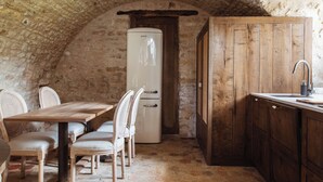 Una cocina rústica con techo de piedra, armarios de madera y suelo de piedra.