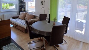 Un espace de vie moderne comprenant une table à manger, des chaises, un canapé et une petite table d’appoint avec des verres à vin.