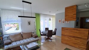 Un salon moderne comprenant un canapé, une table basse en verre, une table à manger avec des chaises et un coin cuisine doté de meubles en bois.