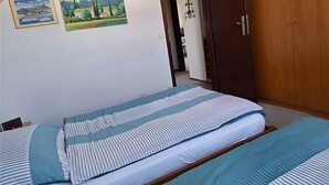 Un dormitorio con una cama, un armario de madera y dos cuadros en la pared.