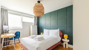 A neatly arranged bedroom with a bed, desk, chair, and bedside lamps. - Stylish Islington Garden Flat Sleeps Four (London)