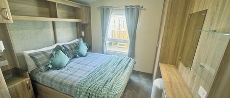 A bedroom with a bed, bedside tables, a wardrobe, and a window with curtains.