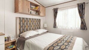 Ein Schlafzimmer mit einem Bett, einem Bücherregal aus Holz, einem Fenster mit Vorhängen und einer Wanduhr.