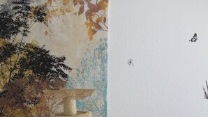 A living room with a black leather sofa, a cat tree, a painting on the wall, and a white pillow with paw prints. - Vacation apartment Zum Vierbeiner (Pirna)